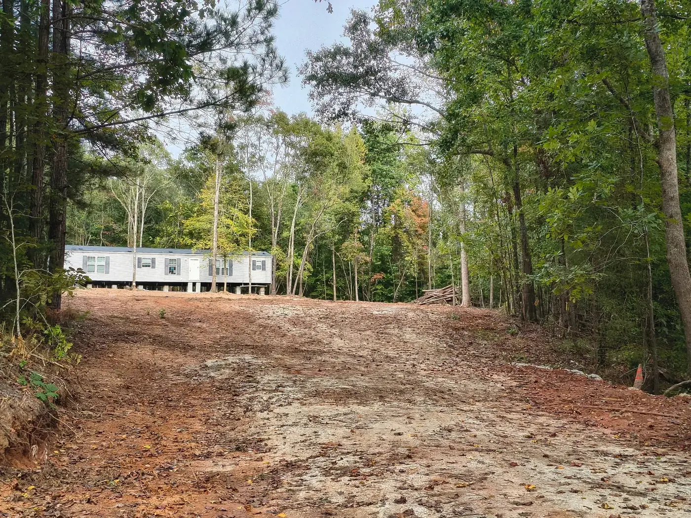 Cleared access drive leading up to a mobile home set on its piers