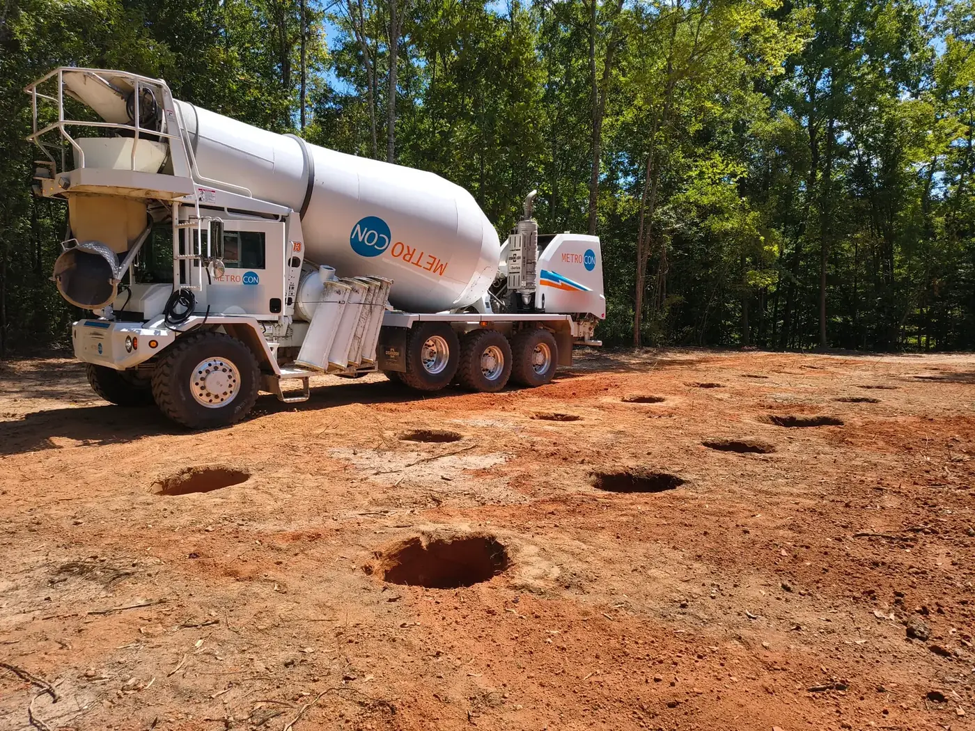Concrete mixer truck on the pad next to the drilled footer holes
