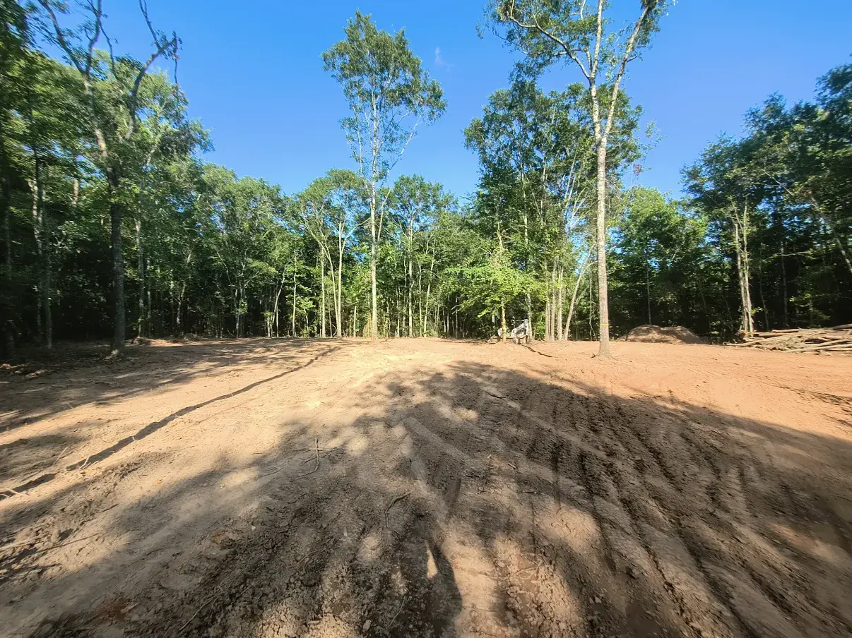 Cleared and graded dirt pad for a mobile home with tread marks from the grading pass