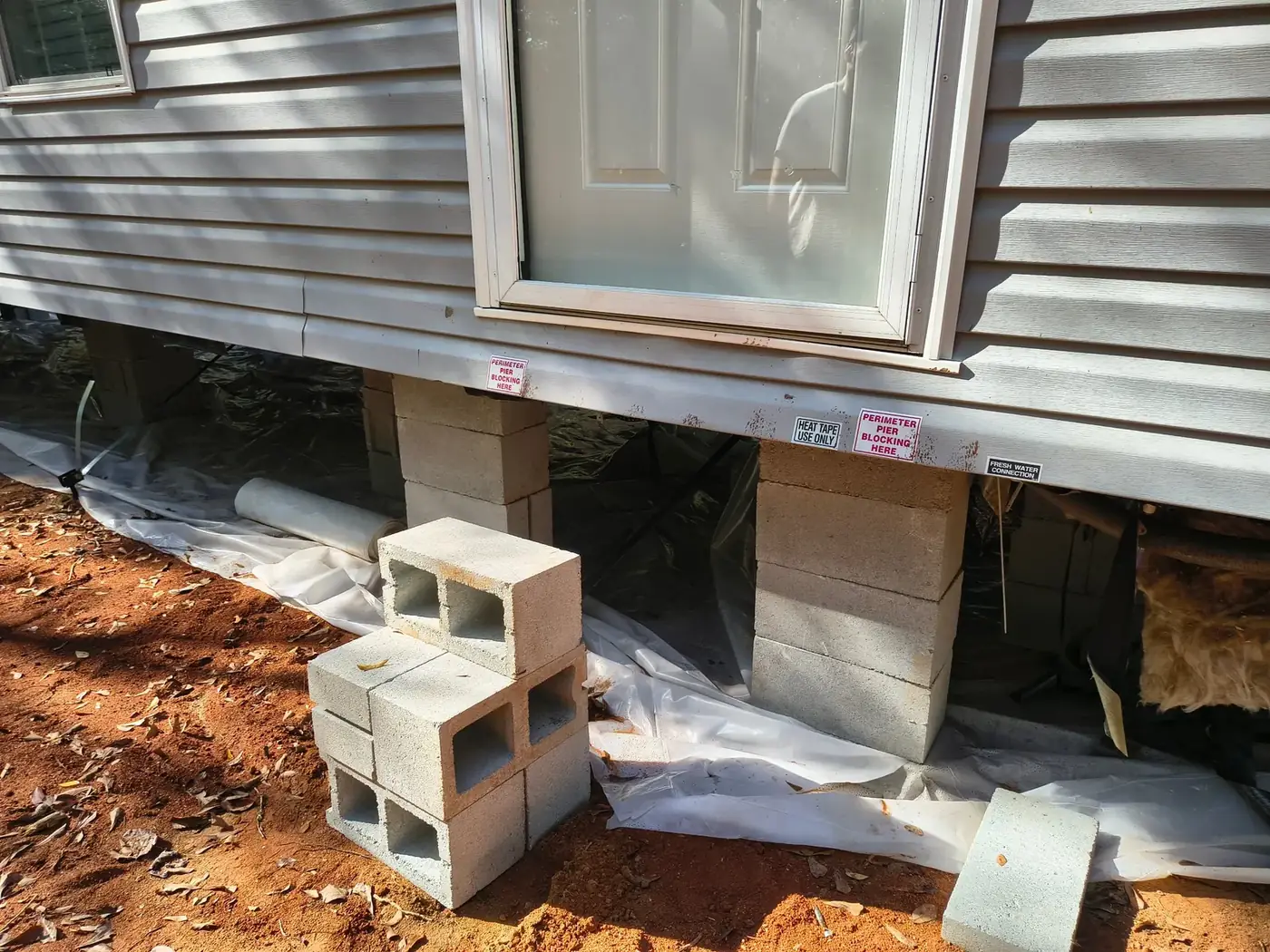 Close-up of stacked concrete block piers under a mobile home with perimeter pier blocking labels
